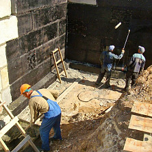 Рабочие производят битумную гидроизоляцию стен